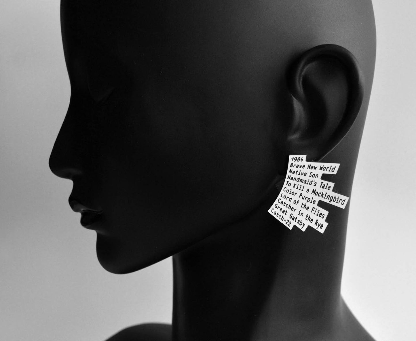 Graphic stud earrings featuring banned books engraved in a jagged stack shape