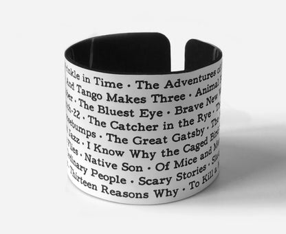 Wide cuff bracelet engraved with a list of banned and challenged book titles, cut from recycled acrylic